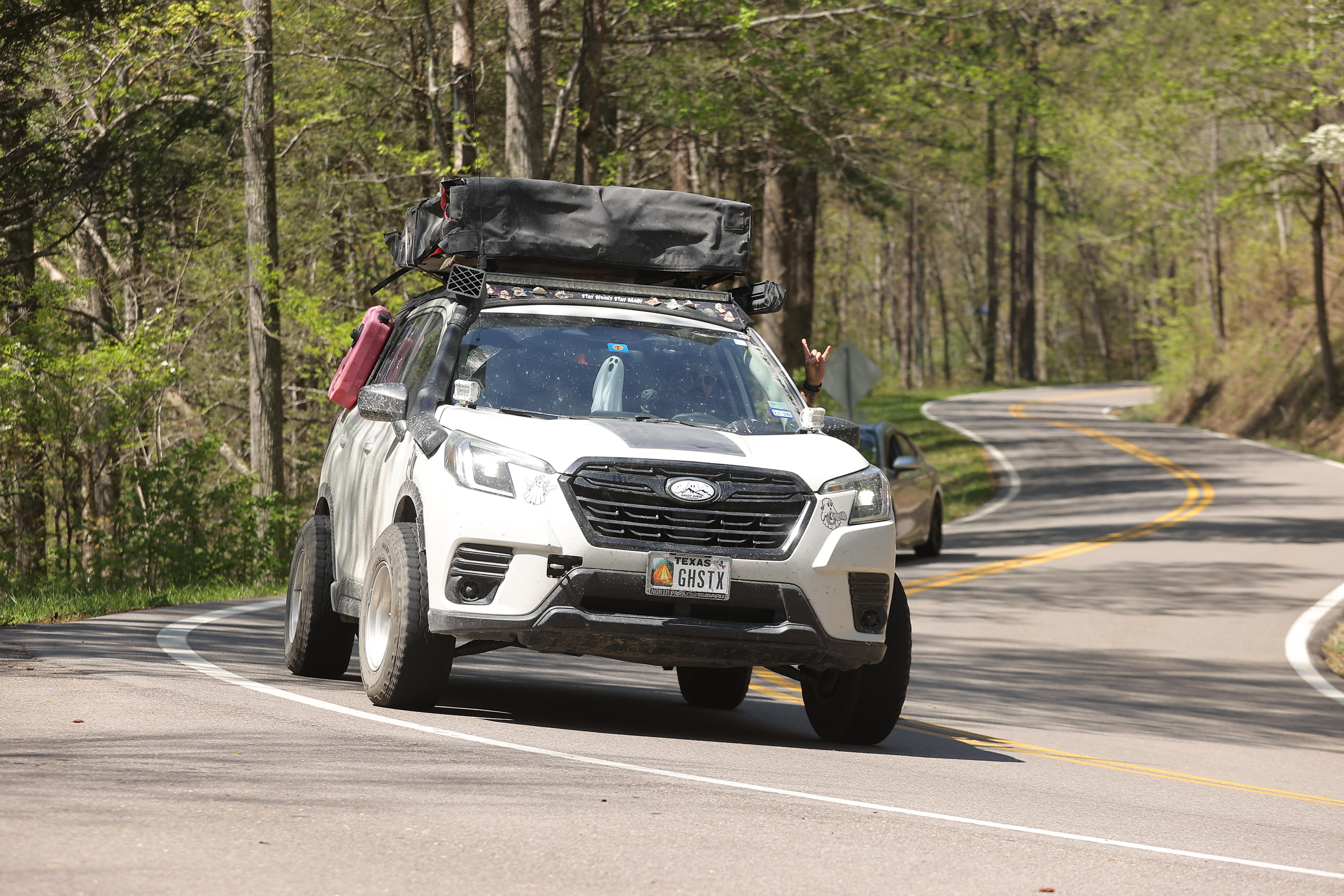 The white Ghost Subaru Forester driving a winding mountain road