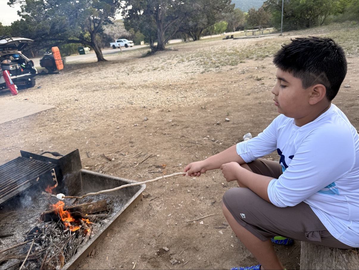 Jonah roasting a marshmallow over a campsite fire